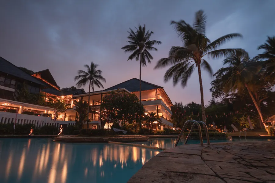 Luxury resort pool deck lined with palm trees at dusk