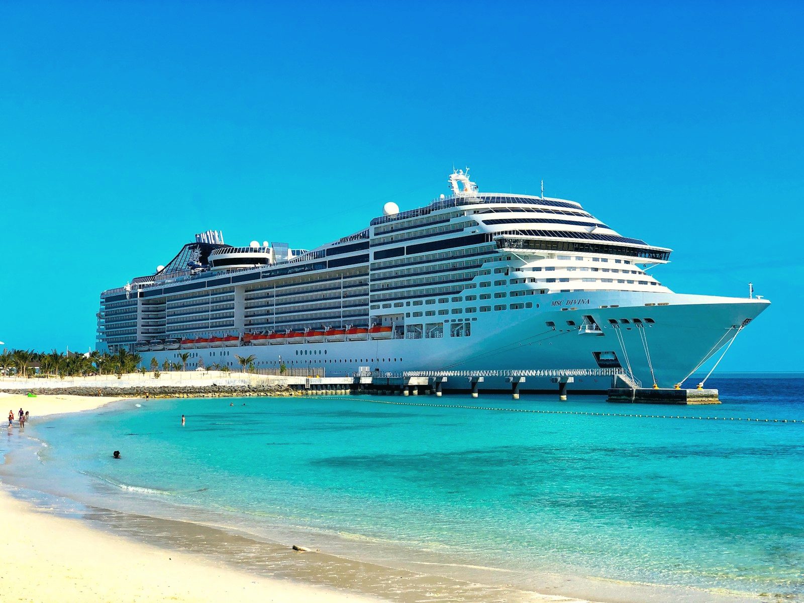 White cruise ship anchored off a turquoise shore