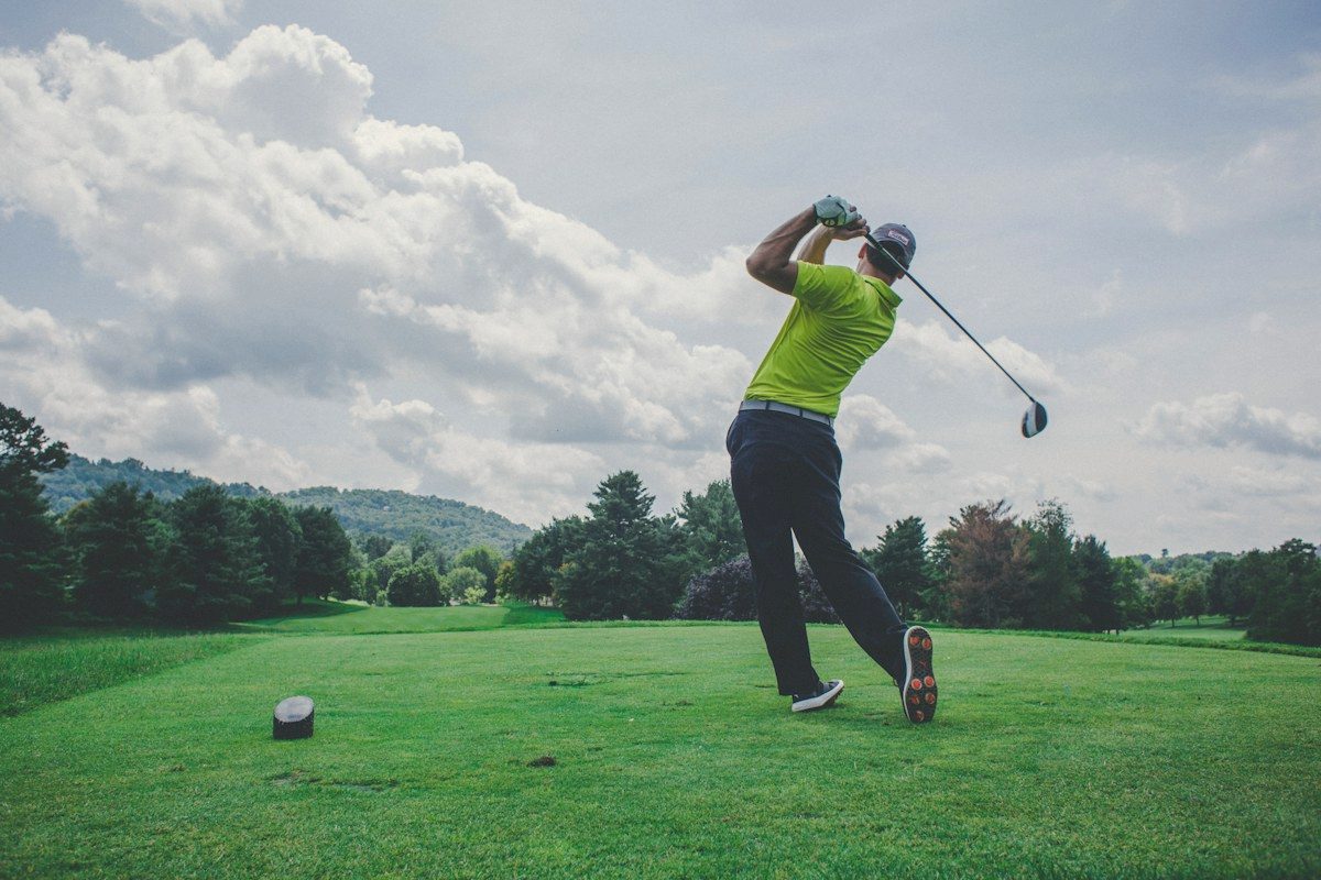 Golfer mid-swing on a sunny fairway