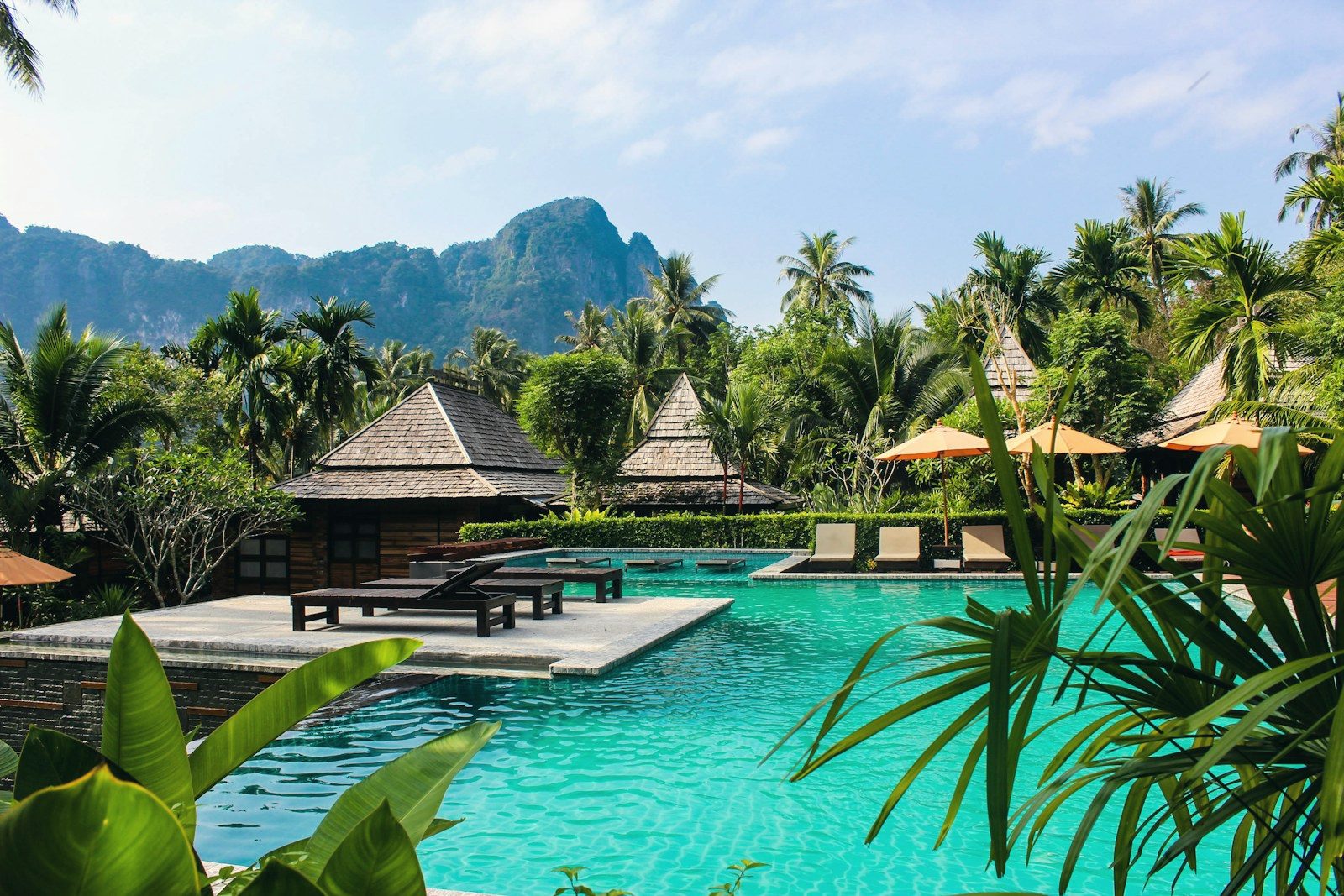 Luxury resort pool deck lined with palm trees at dusk